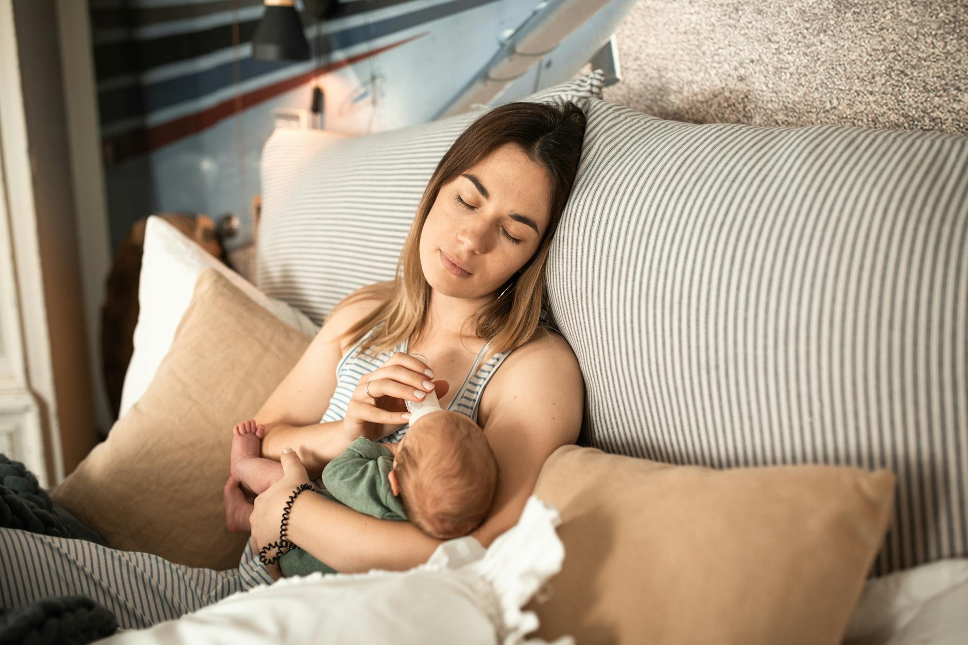 Mama tuląca śpiącego noworodka w domowym zaciszu