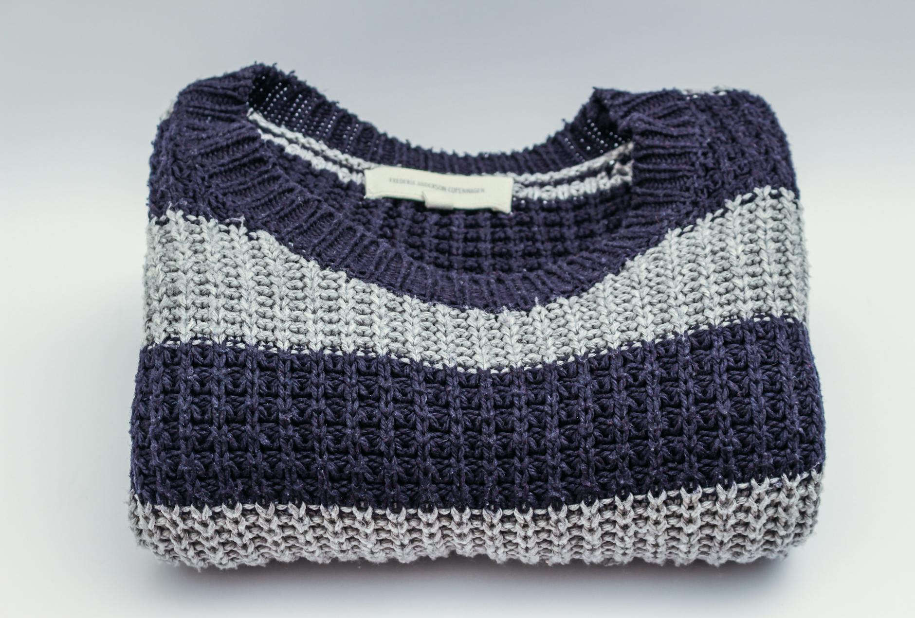 Zimowy sweter w niebiesko-białe pasy leżący jako rekwizyt do stylizacji
