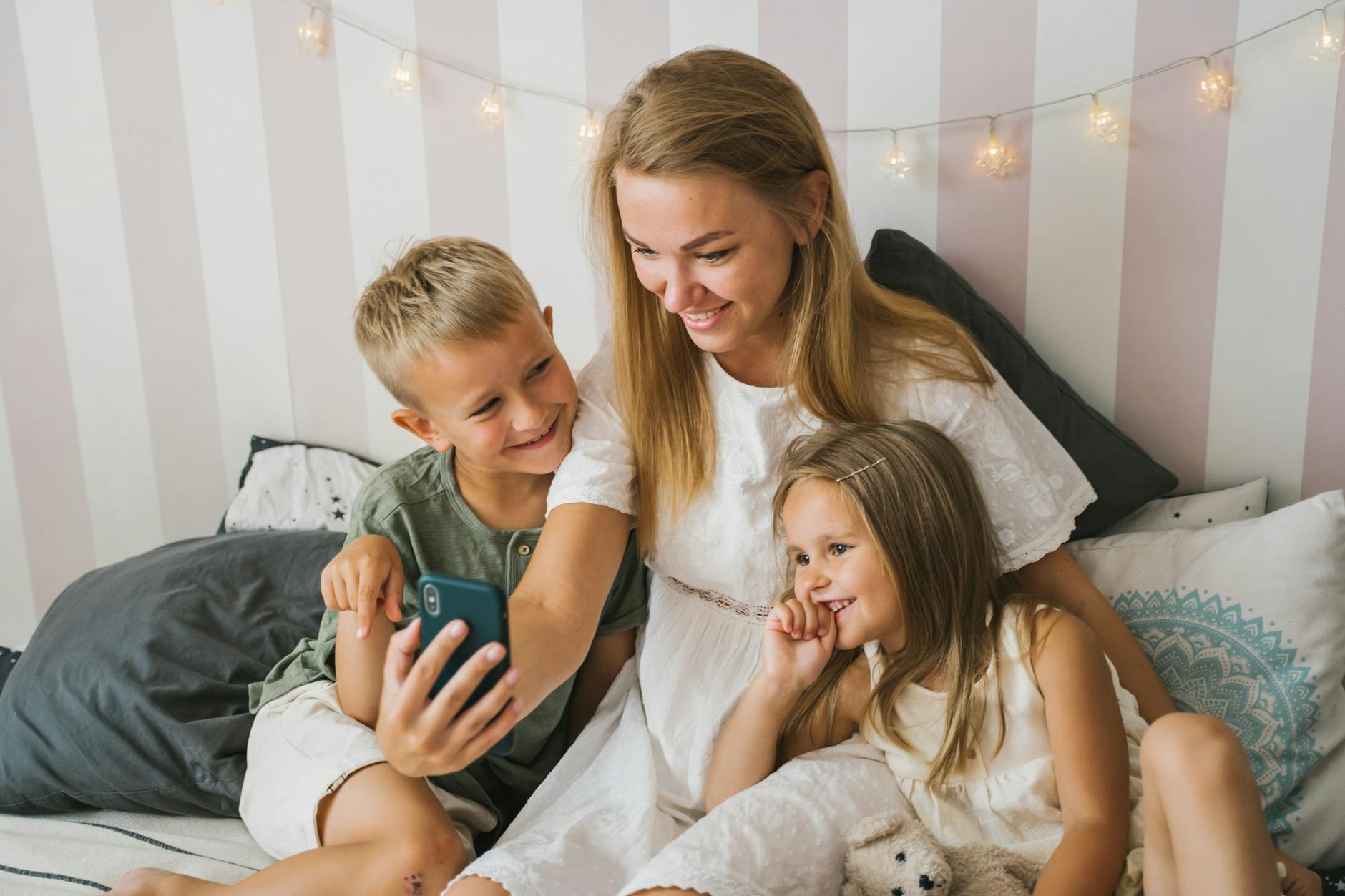 Mama z dwójką dzieci ogląda coś w smartfonie i śmieje się